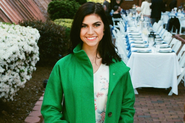 photo of recent graduate in a green jacket