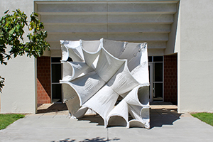 white sculpture outside of building composed of scalloped forms to make a cube