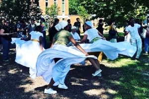 dancers in white perform ring shout outdoors