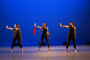 three dancers in all black with their left hand extremed and they are looking at their hand