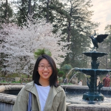 Jane outside in front of a fountain and cherry tree