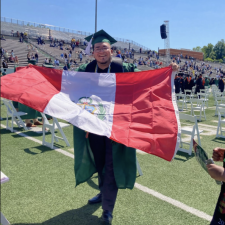Gerson Berrio in his cap and gown holding a flag
