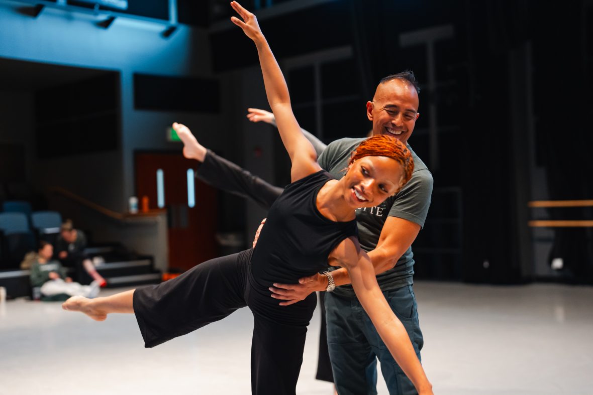 dance student in side tilt with professor giving direction