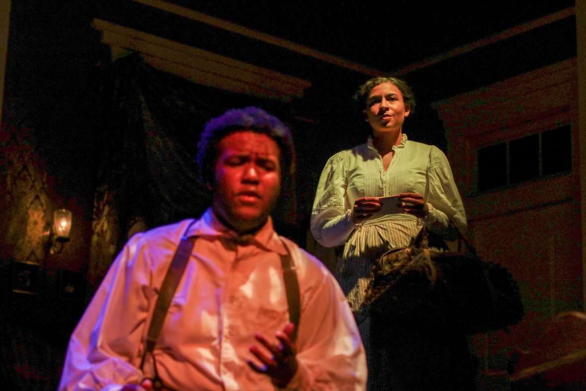 Male student on stage in front of a female student in the production, Intimate Apparel