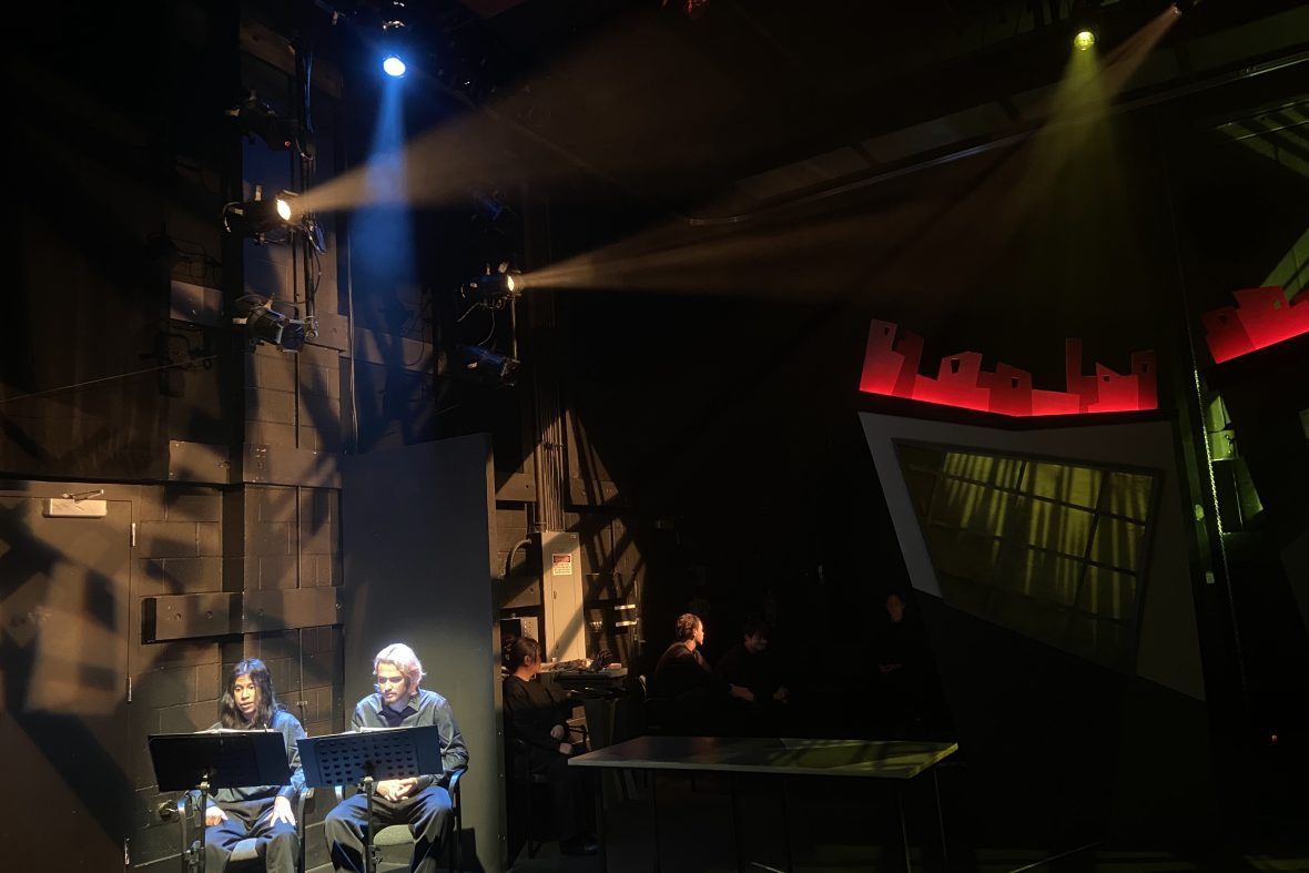 Far away shot of stage lighting with two directing students with headsets in the corner