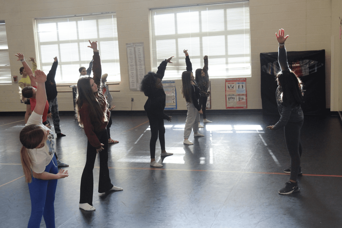 dance student in classroom leading middle school students in a warm up stretch