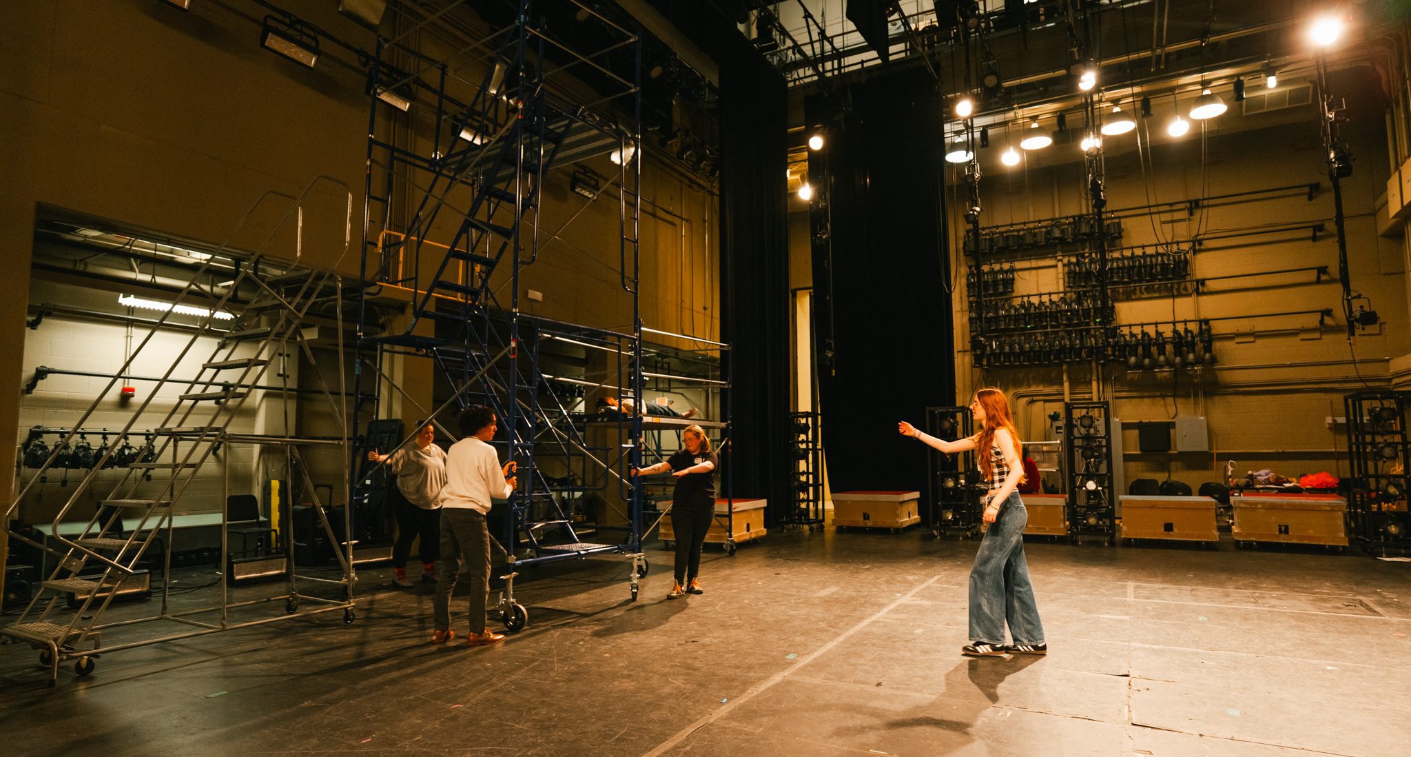 students on an exposed stage, curtain back, with a lift 