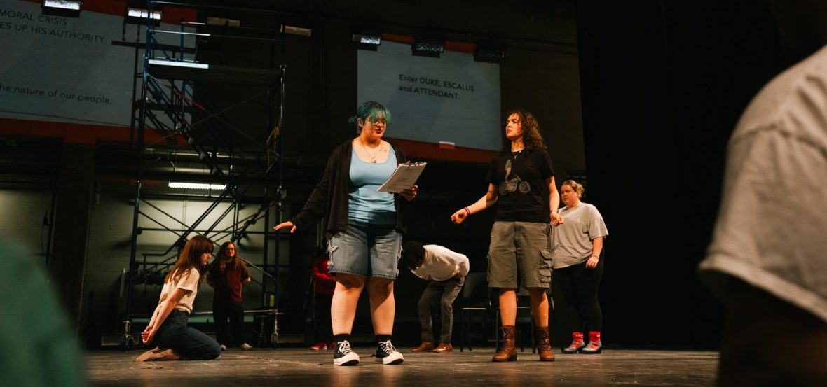 students on a stage during a workshop, one holding a script