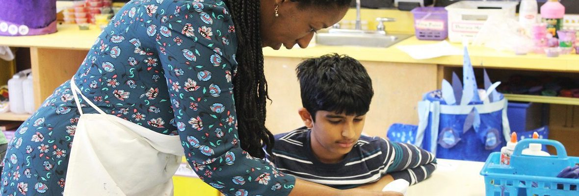 art ed teacher working with an elementary school student on an art project