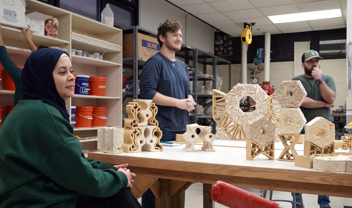 students siting at a table with recyclable material sculptures