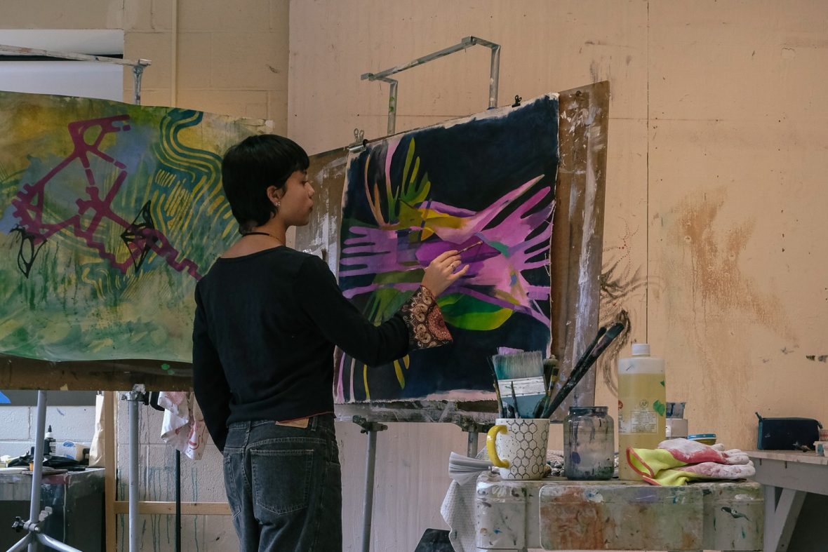 student painting in the studio on a black canvas