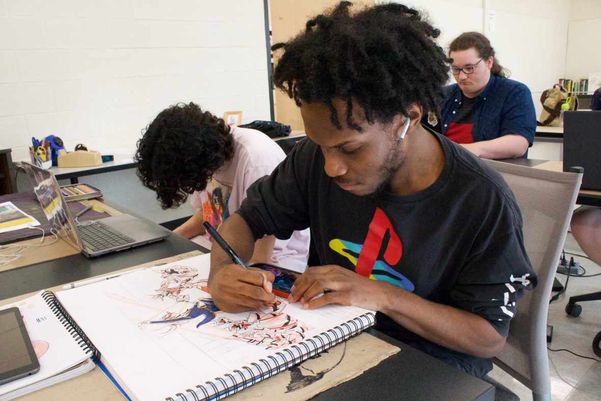 student with a large sketch book, drawing