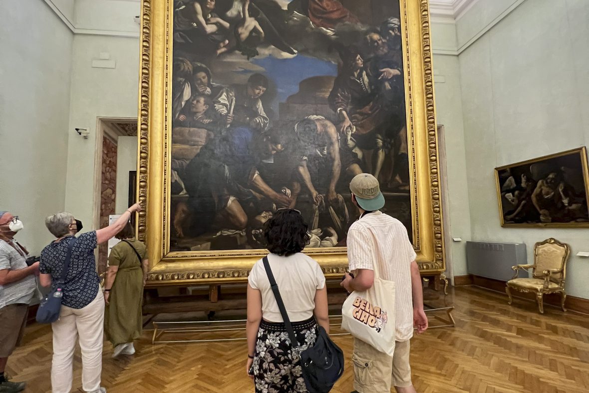 two students looking at a large wall sized roman painting