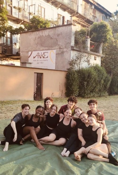 Group of dance students and Italian dance students sitting on the ground outside in a field