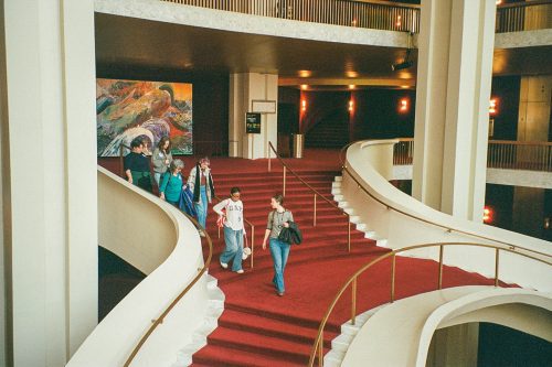 students walking down a large red staircase 