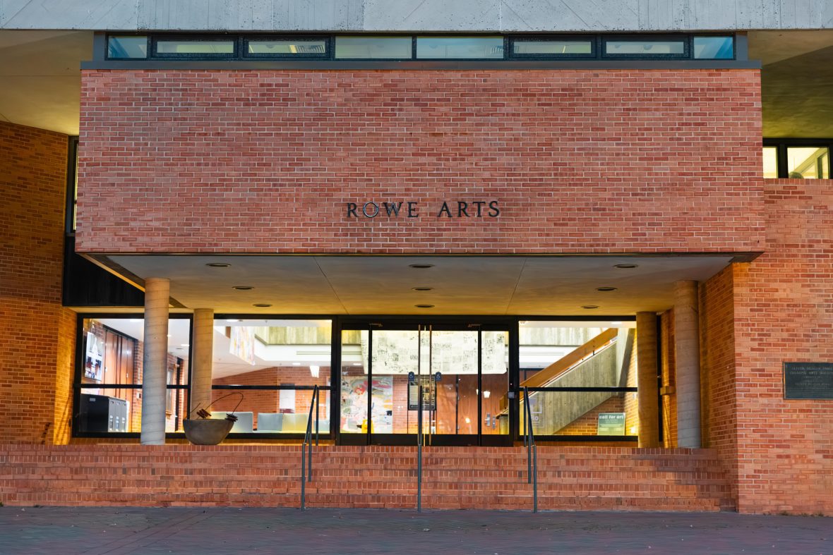 the exterior of Rowe Arts brick building at night with lights on inside