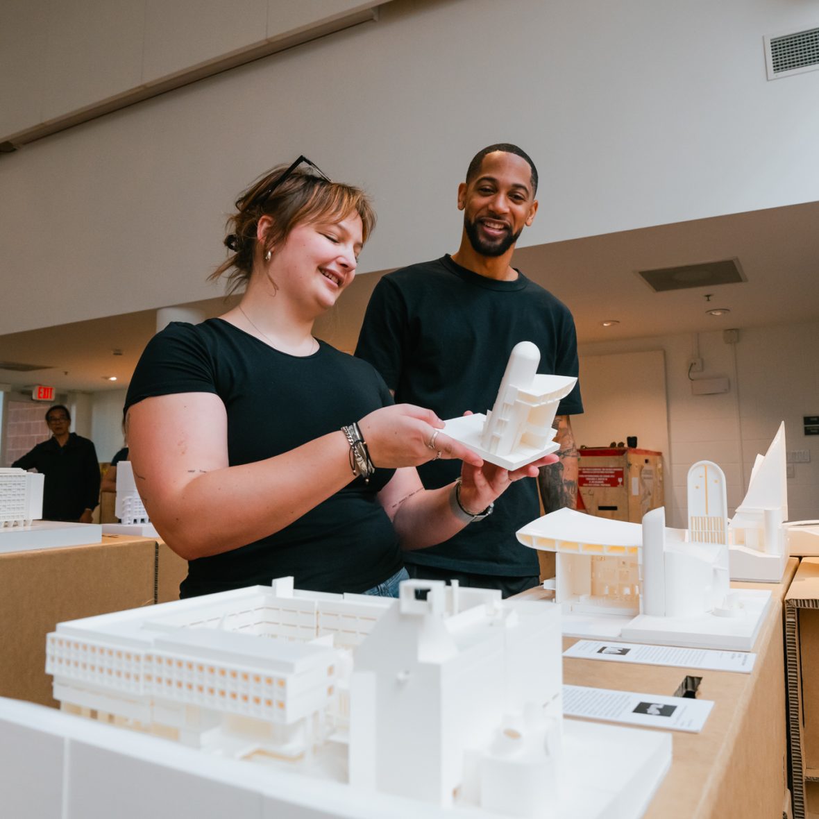 Two architecture students looking at a model in the gallery