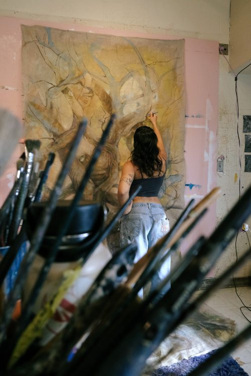 student with paint brushes in front of her
