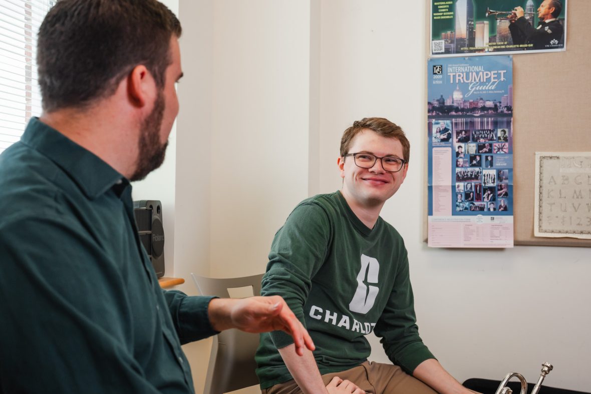 Student sitting in Charlotte shirt talking to professor in a private lesson