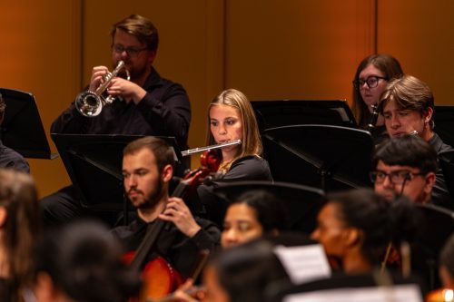 A female playing the flute focused in orchestra concert