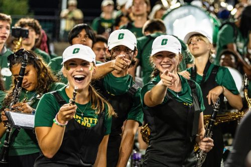 Women in the marching band pointing and smiling at the camera