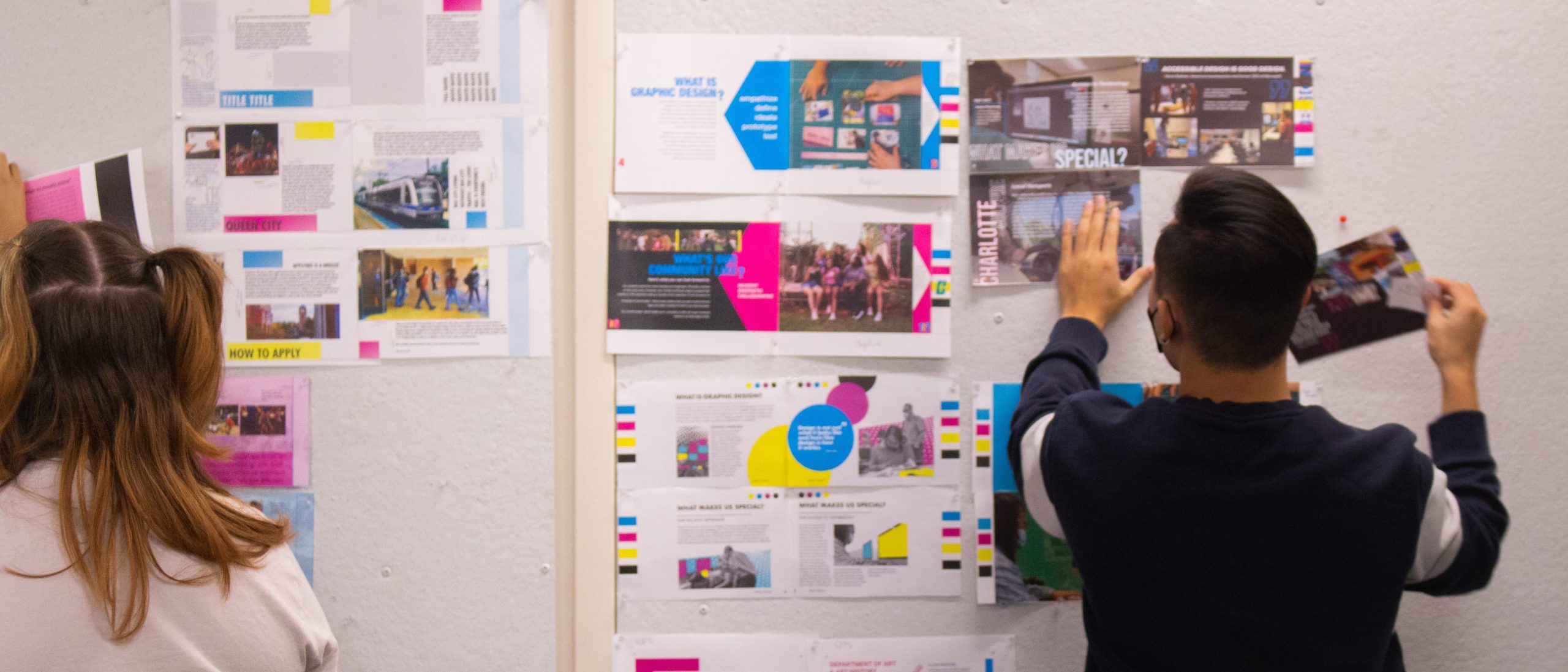 Student pinning up graphic design presentation slides