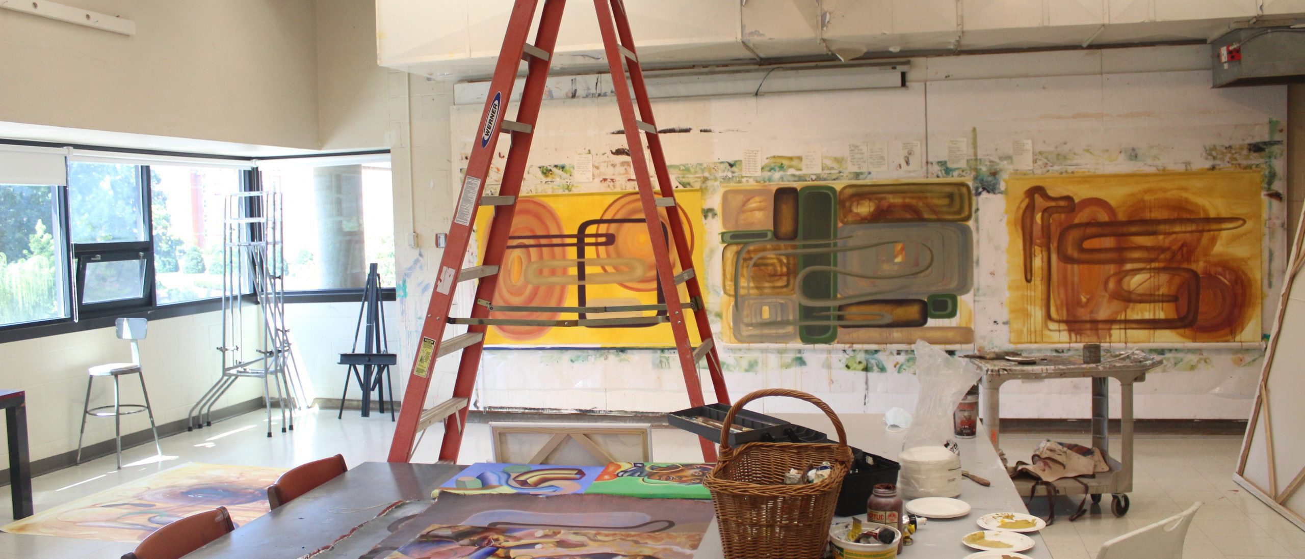 View of the painting studio with a ladder and orange paintings on the wall