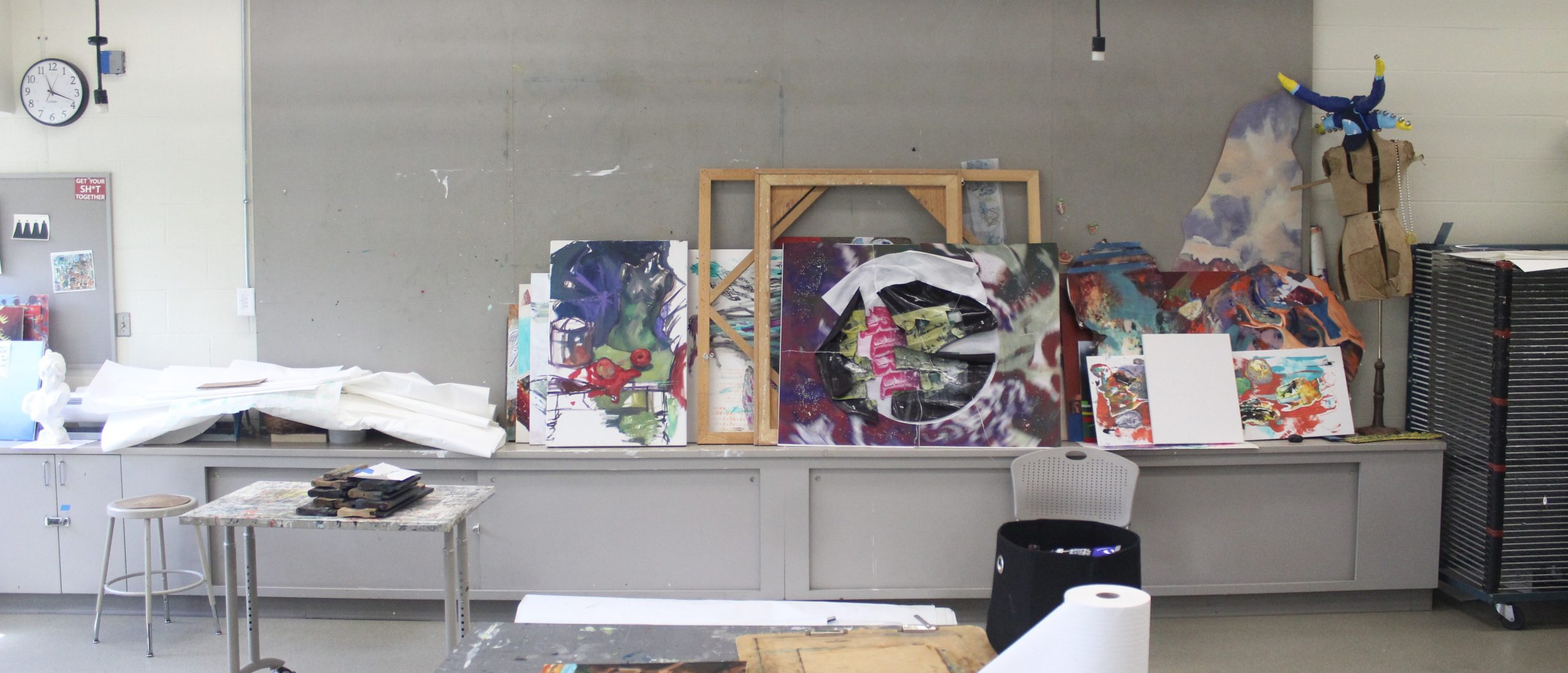 Paintings waiting to be hung in a studio