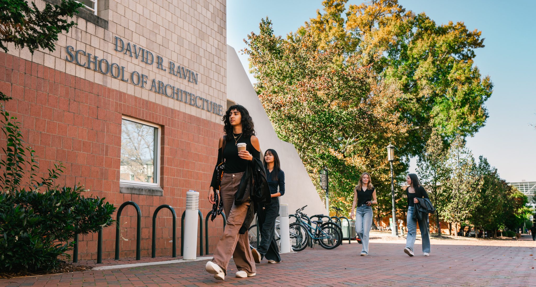 students walking into Storrs, one holding a coffee