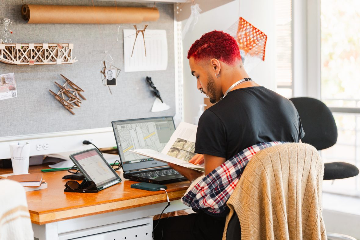 student reading a text book at his work station in the studio