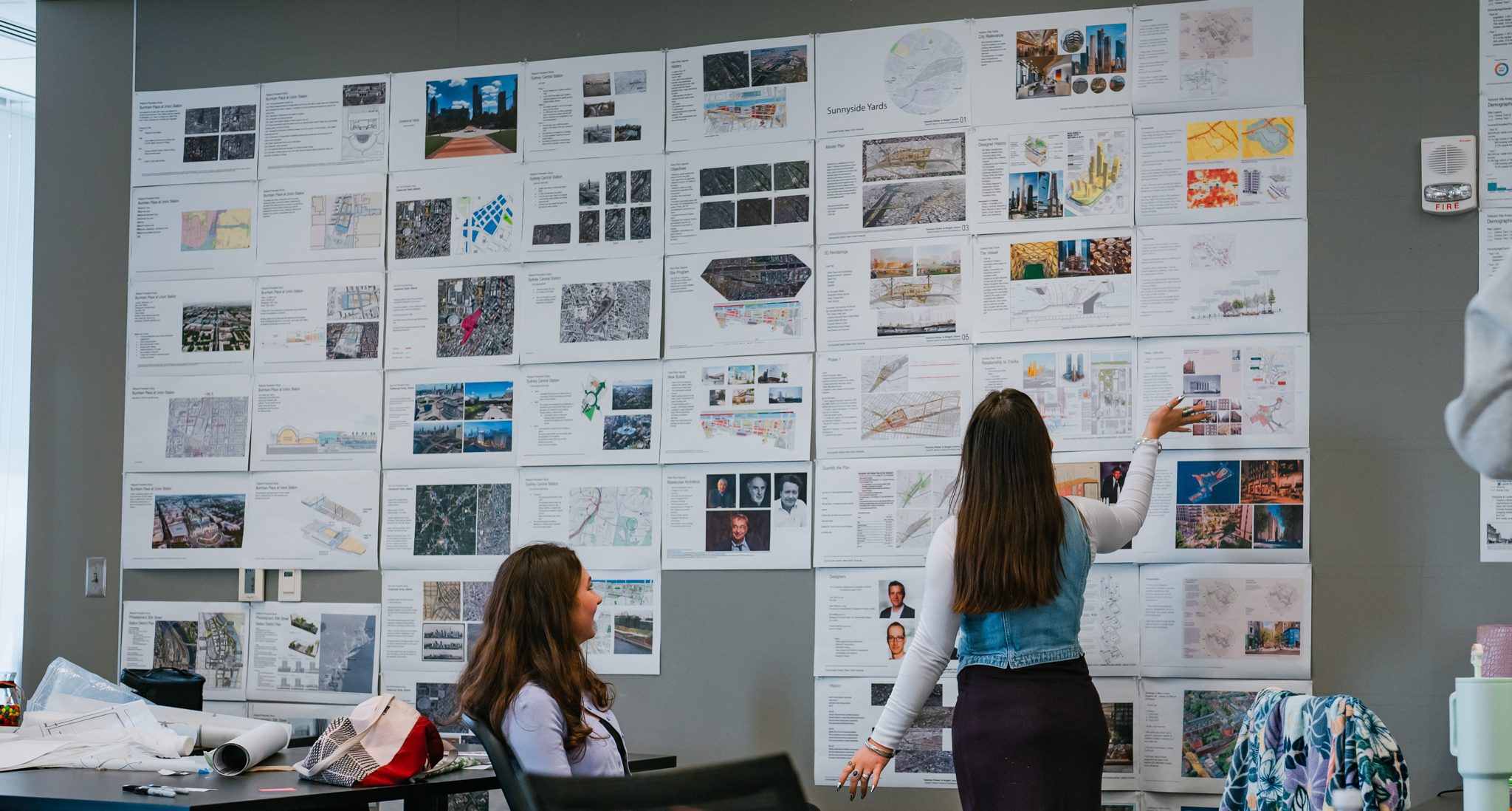 students looking at posters of their work on a board