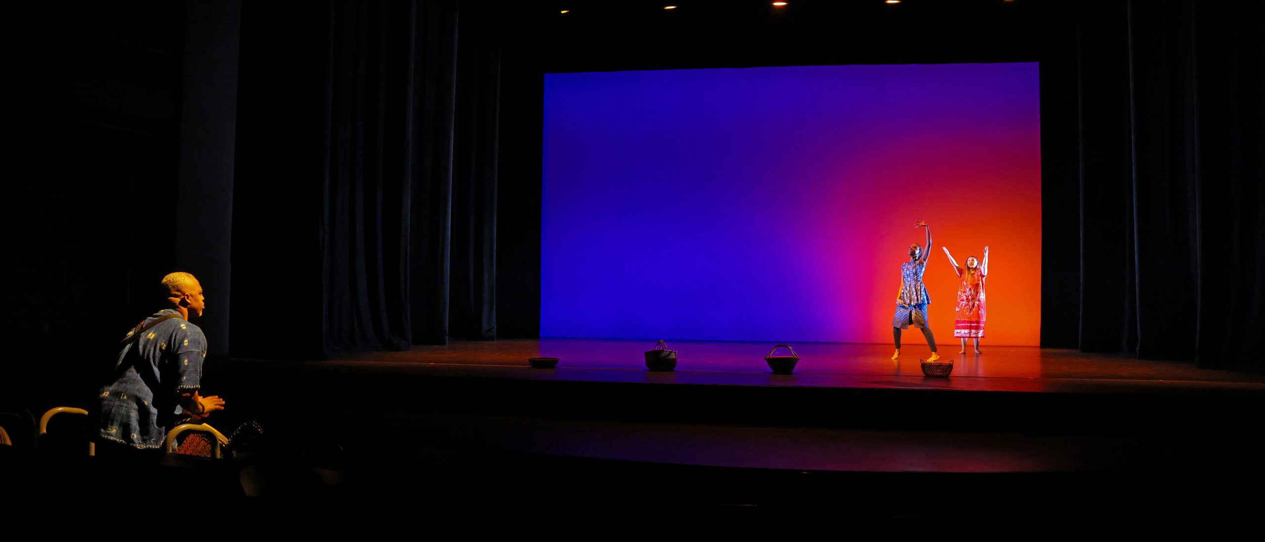 Dancers in an Afro-Brazilian piece performing on stage with colorful lighting and musician
