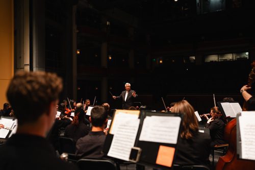 View from the back of the stage of conductor with students in front
