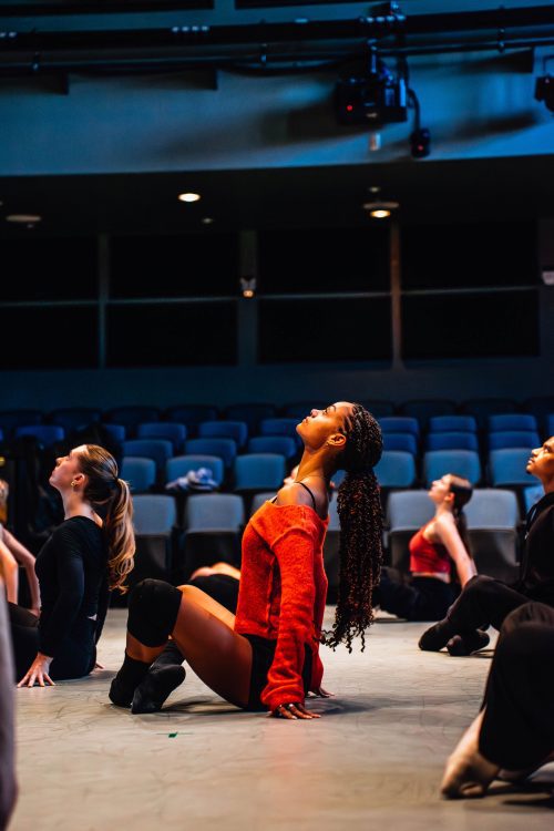 student on the floor of dance studio doing a floor exercise