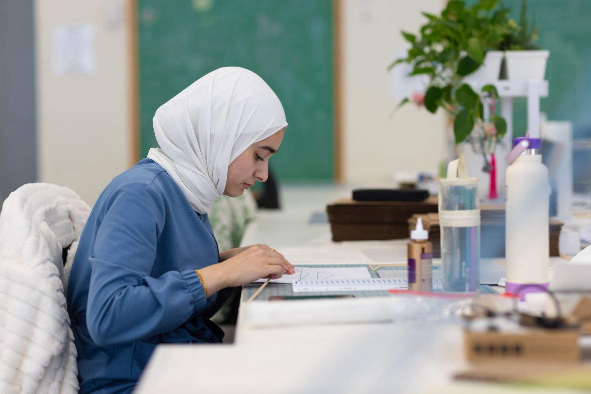 student in head covering working on a project in the studio