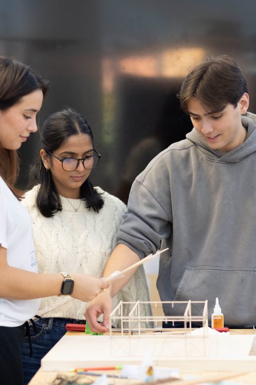 three architecture students looking at their model