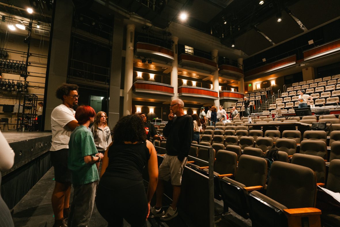 a group of students in the Belk Theater with professor Conkie, with theater seats behind them