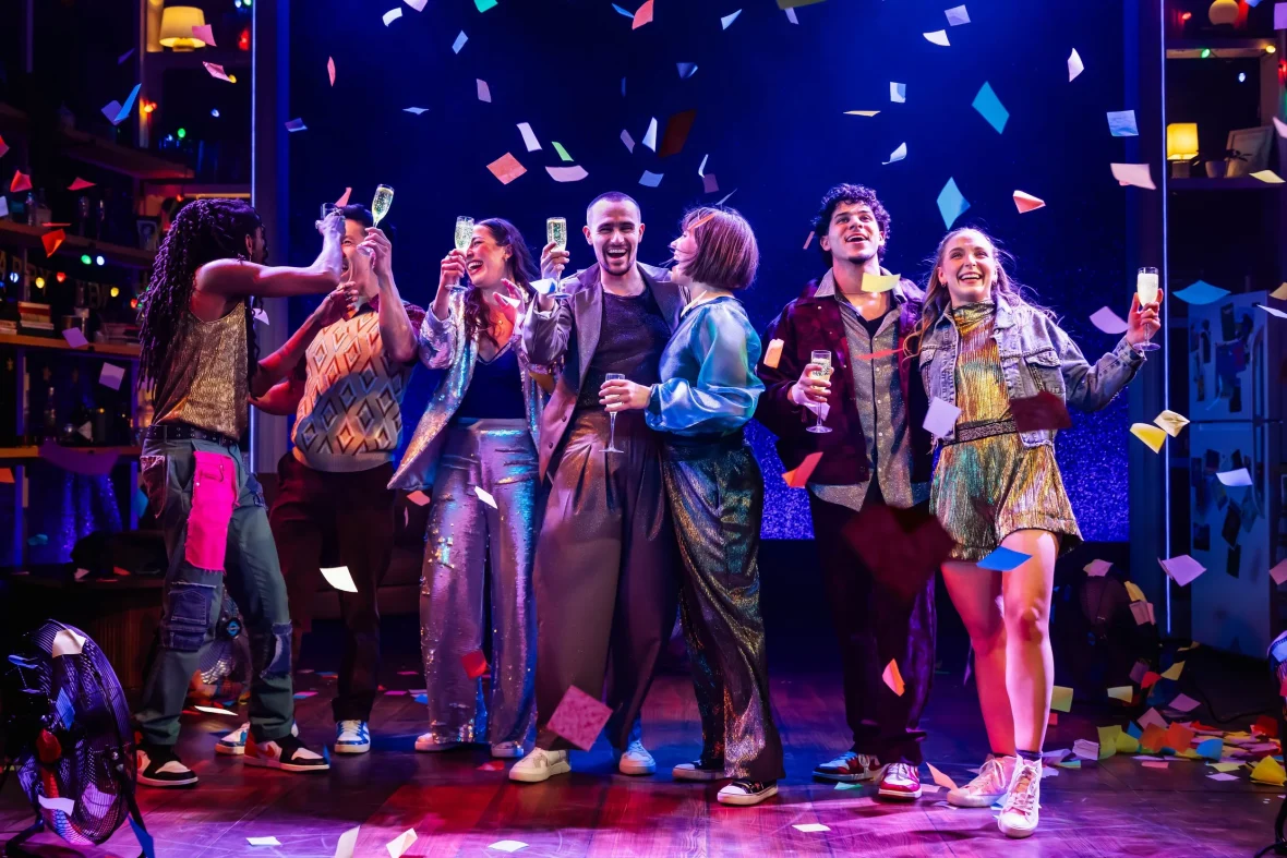 cast on stage in dark lighting, post it notes flying behind them
