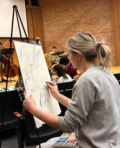 an art student drawing with music students behind her