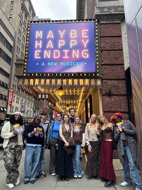 group of students standing under a broadway theatre sign