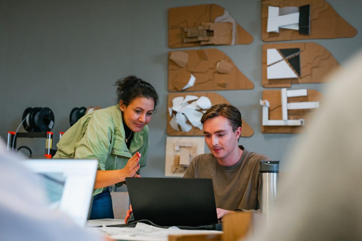 professor with student, looking at laptop