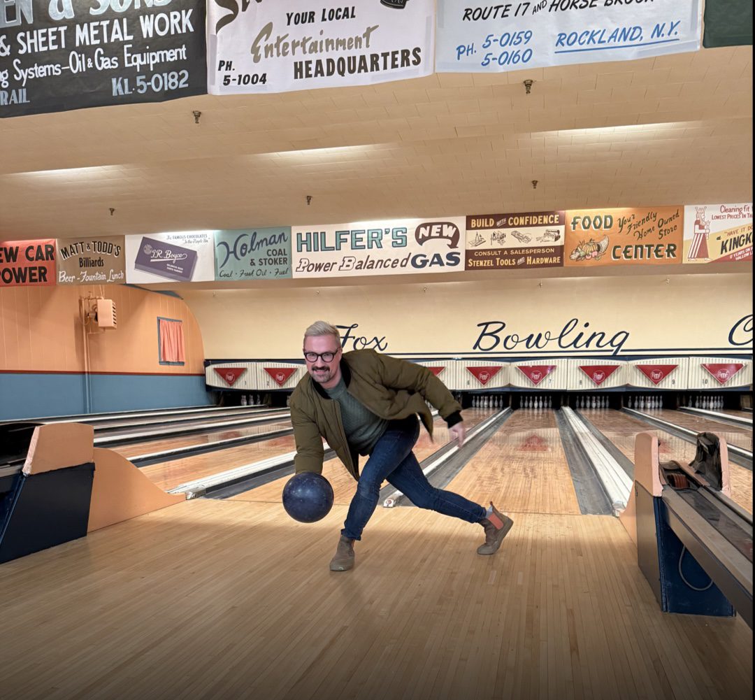 man bowling toward the camera in an vintage style bowling alley set