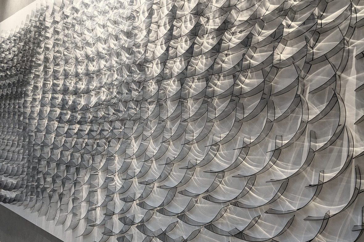 Art piece taking up full wall, silver waves of material