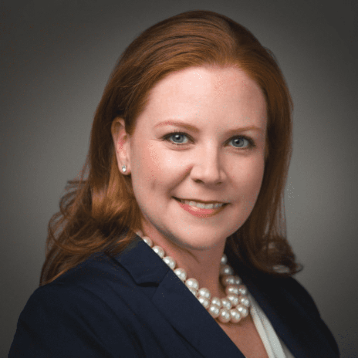Headshot of Leslie Antoniel, wearing a pearl necklace and a blue blazer