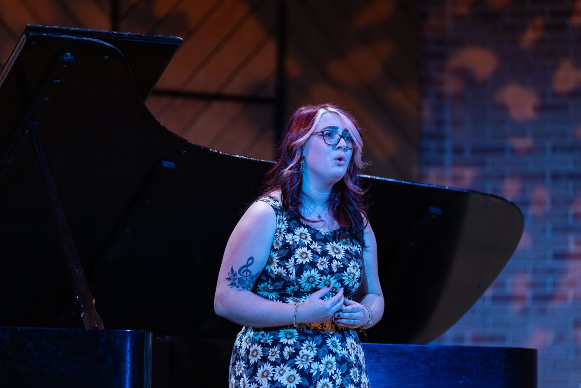 Singer on stage with purple lighting, singing