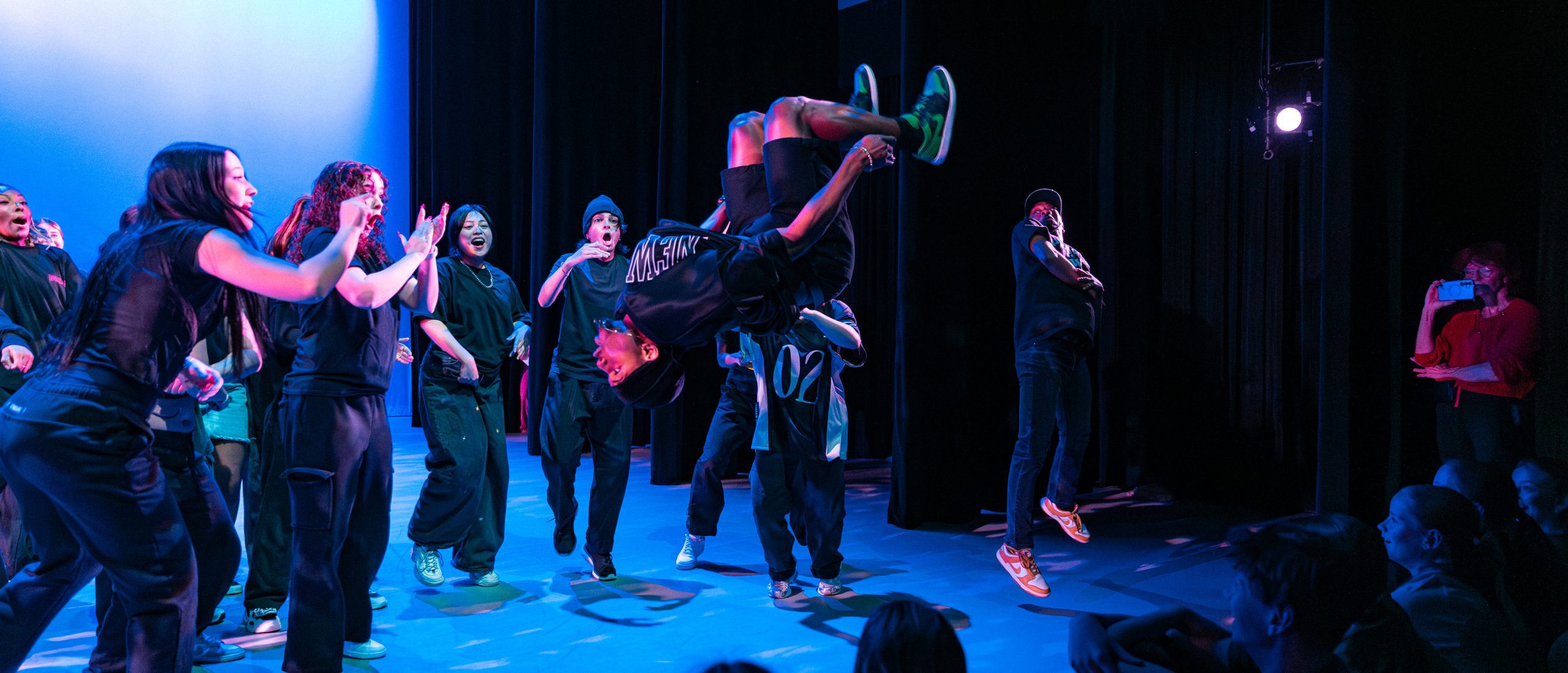 Hip Hop dance students performing in studio under blue lighting