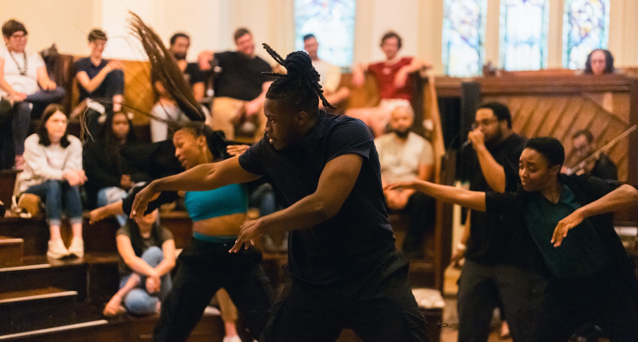 Dancers and vocalist in performance with audience behind them watching