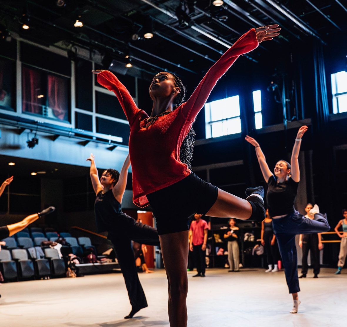Dance student in arabesque in a red shirt
