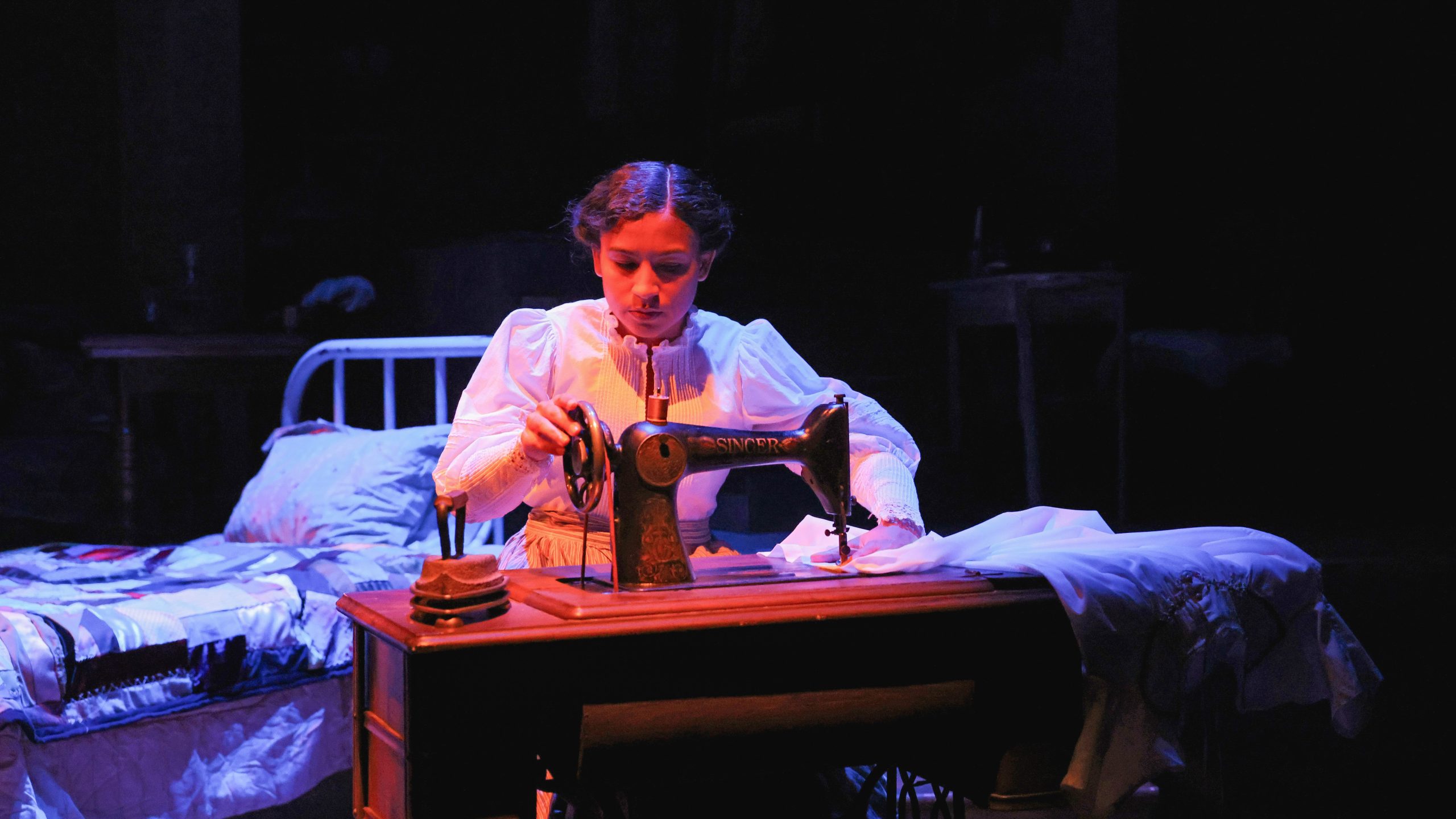 Chloe Shade sitting at a sewing machine on the set of Intimate Apparel.