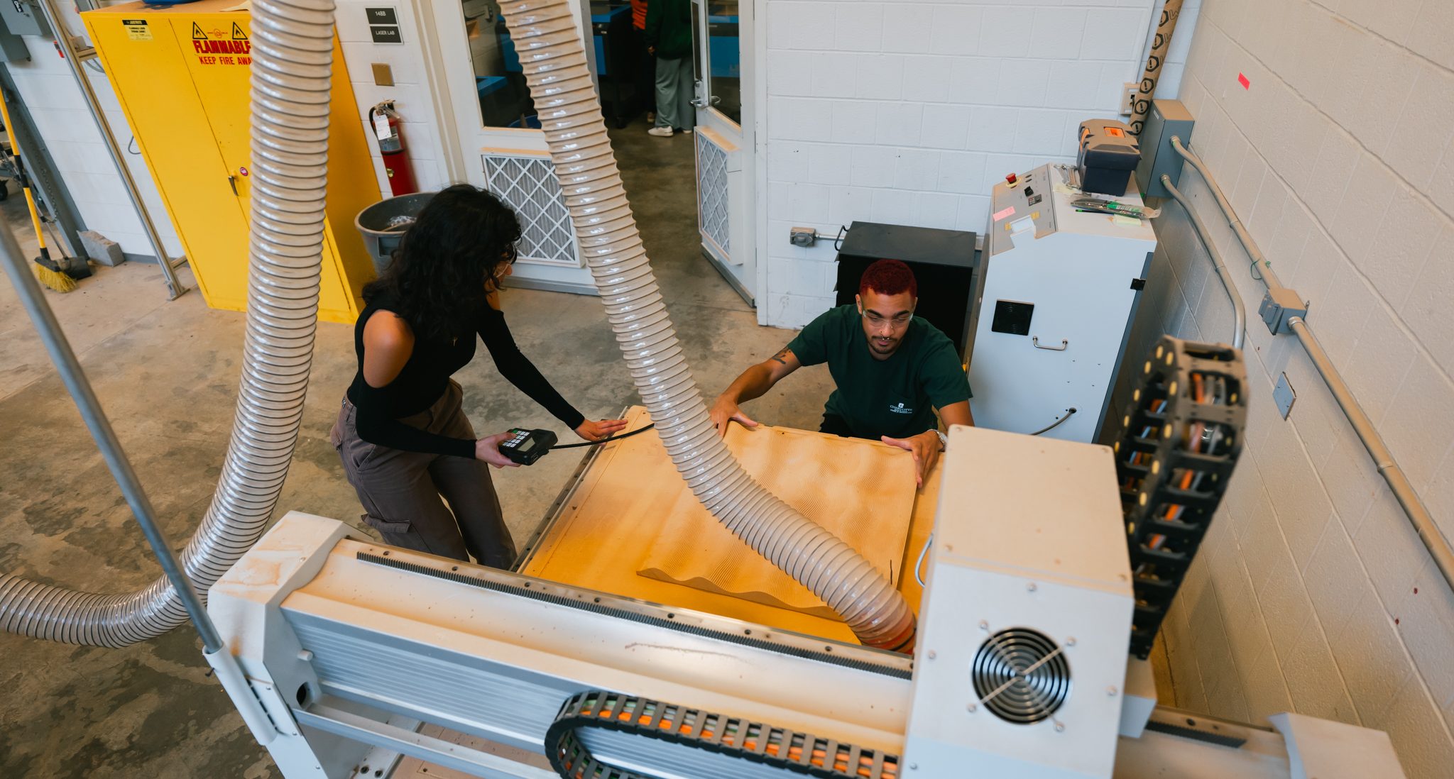 Two students working at a router table in the fabrication lab